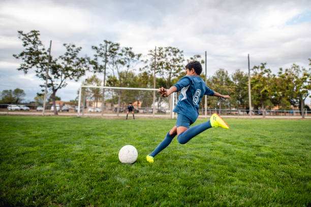 athletic mixed race boy footballer approaching ball for kick - chutando bola imagens e fotografias de stock