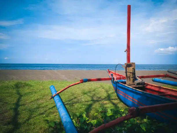 Beach Scenery And Traditional Wooden Fishing Boat Moored On The Grass By The Beach, North Bali, Indonesia