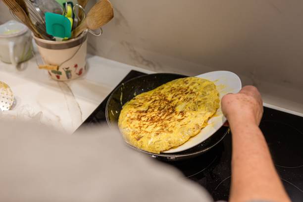 Woman cooking a potato omelet Woman cooking a Spanish tortilla de patatas (potato omelet) tortilla de patatas stock pictures, royalty-free photos & images