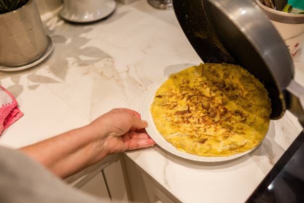 kobieta gotująca hiszpańską tortillę de patatas (omlet ziemniaczany) - tortilla de patatas zdjęcia i obrazy z banku zdjęć