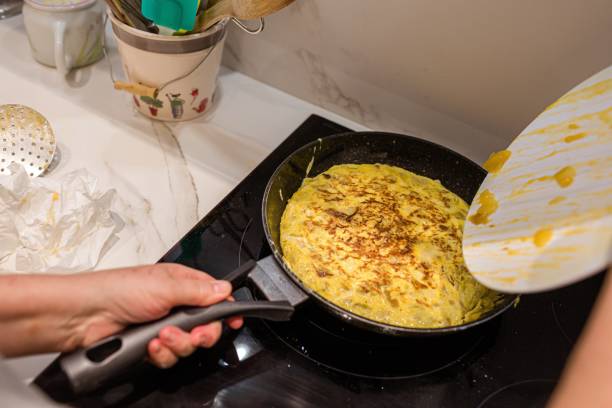 kobieta gotująca hiszpańską tortillę de patatas (omlet ziemniaczany) - tortilla de patatas zdjęcia i obrazy z banku zdjęć