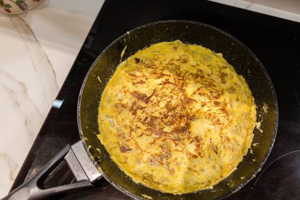 donna che cucina una tortilla de patatas spagnola (frittata di patate) - tortilla de patatas foto e immagini stock