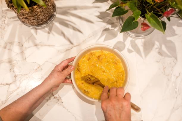 Older woman's hands mixing eggs and potatoes with onions to cook a potato omelet. Older woman's hands mixing eggs and potatoes with onions to cook a potato omelet. tortilla de patatas stock pictures, royalty-free photos & images