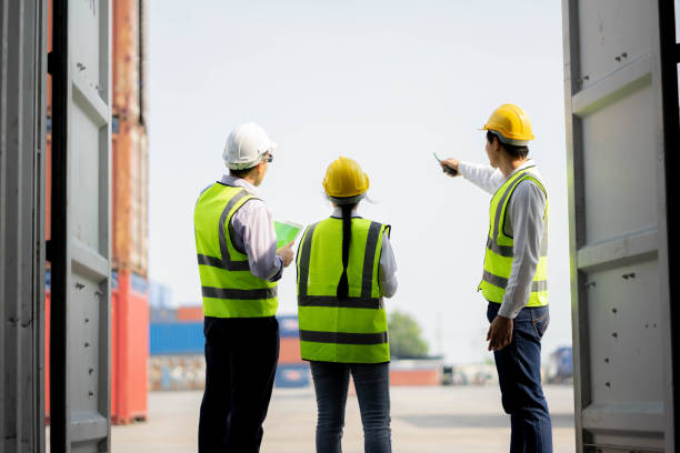 istock Team engineer dock control logistics worker wear safety helmets and protect suite open cargo container door and working and checking product with taplets. 1306791808