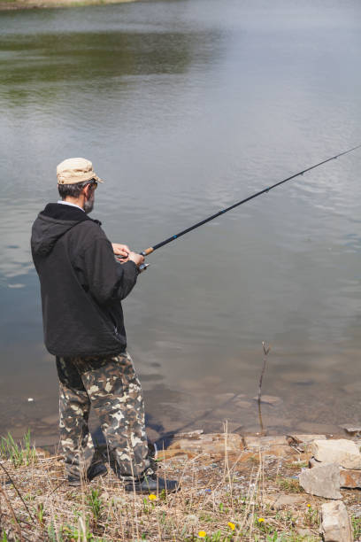 istock Fisherman with beard catches fish on river bank 1306793476