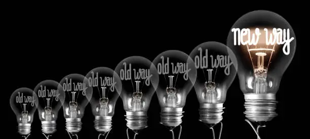 Large group of shining and dimmed light bulbs with fibers in a shape of New and Old Way words isolated on black background. Concept of Innovation, Development and Success