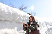 積み重ねられた雪の間の道で雪をぶむ美しい若い女性