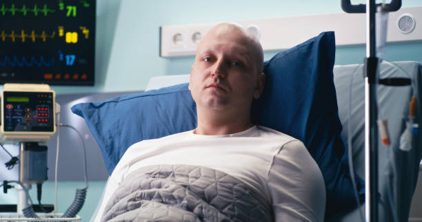 Cancer patient on hospital bed Bald man lying on bed and looking at camera during recovery in modern oncology clinic real time stock pictures, royalty-free photos & images