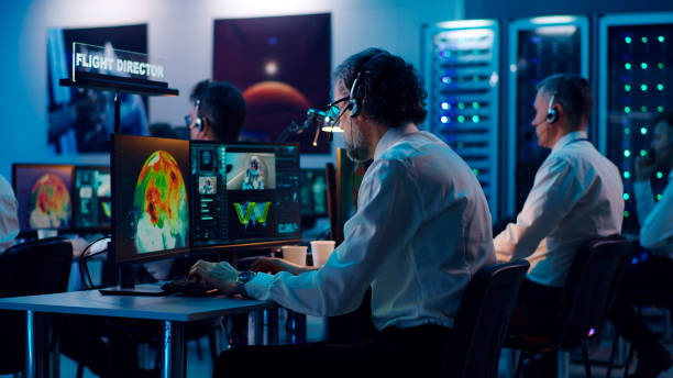 Senior man helping colleague during rocket launch View of aged man giving advice to mature coworker using computer during spacecraft launch in flight control center real time stock pictures, royalty-free photos & images