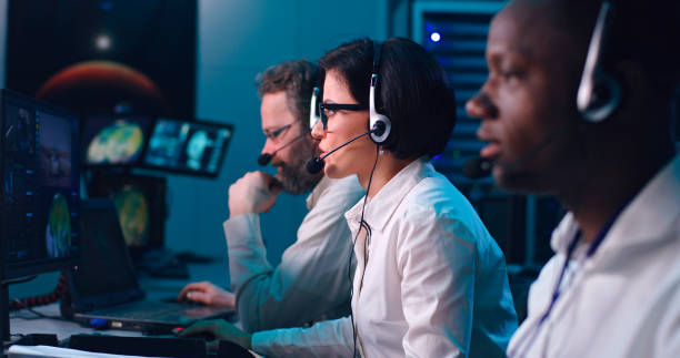 Multiethnic operators suffering mission failure Rack focus of diverse men and women rubbing face and gesturing in frustration after mission failure in flight control center control room stock pictures, royalty-free photos & images