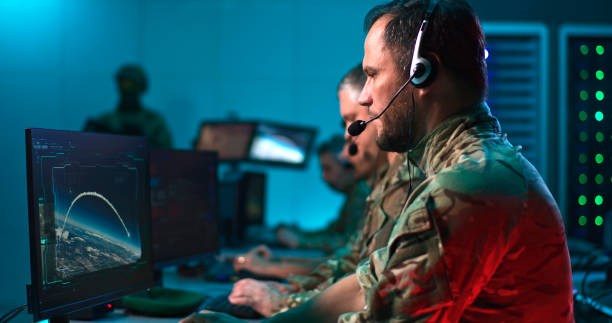 Military commander using computers during world war Pan around view of bearded military man with headset giving commands and using computer to launch nuclear missile while working in control center during world war. real time stock pictures, royalty-free photos & images