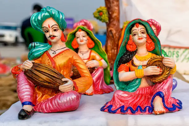 Beautiful handmade dolls of miniature villagers performing their daily chores is displayed in a shop for sale in blurred background. Indian handicraft.
