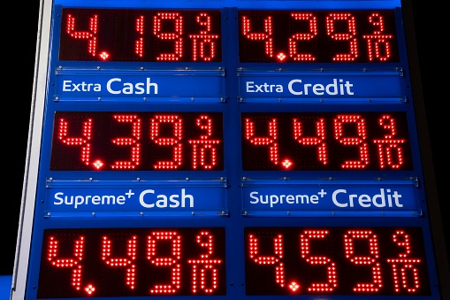 Close up on a gas station price sign with red illuminated numbers.