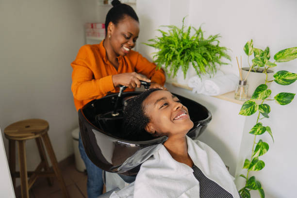 Washing hair in a hair salon Photo of an African American hairdresser, washing hair to a customer with an Afro hair style black woman washing hair stock pictures, royalty-free photos & images