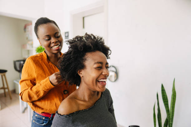 In a hair salon Photo of a young African American hairdresser, blow drying hair of her customer in a hair salon. hair salon stock pictures, royalty-free photos & images