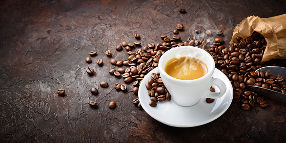 Steaming espresso on brown background, close-up, space for text.