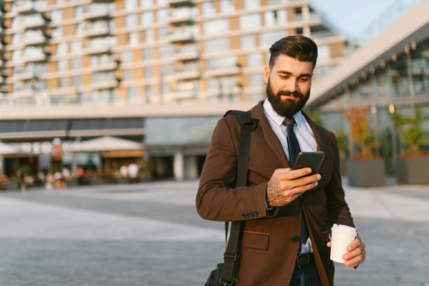 istock Handsome businessman using mobile phone and holding coffee cup 1306820099