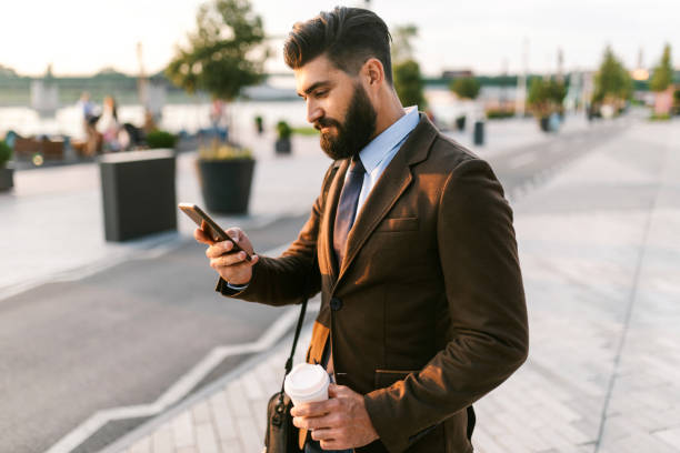 istock Handsome young man holding mobile phone and text messaging 1306820275