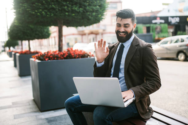 istock Handsome businessman sitting on a bench and having a video call on laptop 1306820394