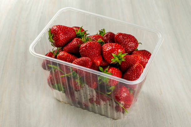 istock a clear plastic container with ripe juicy red strawberries is on table 1306825949