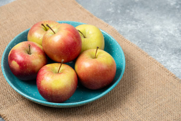 istock Blue bowl full of fresh apples on marble background 1306826924