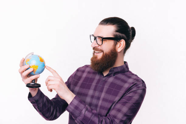 istock Photo of handsome young man with beard pointing at globe over white background 1306827747