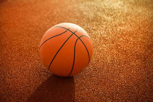 Close-up of orange basketball ball on a empty basketball court.