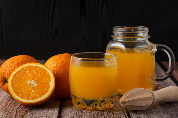 istock Sliced oranges with juice in the glass jar and cup 1306836363