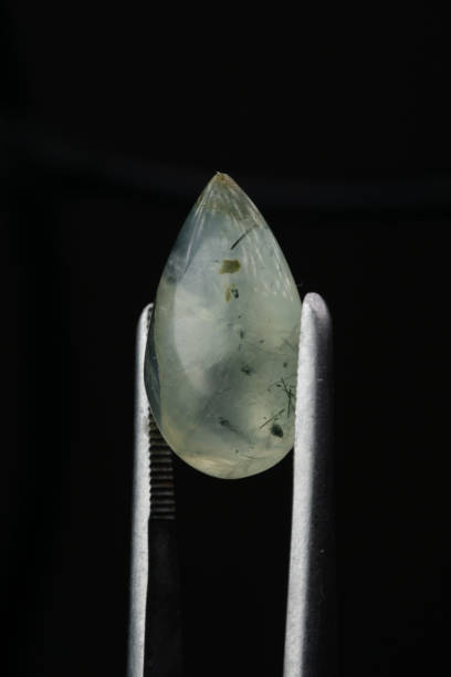 istock Natural prehnite stone in tweezers on a black background 1306837618