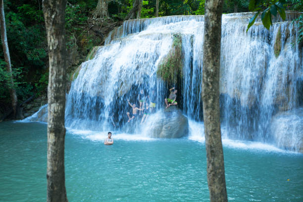 Bathing thai people in Erawan waterfalls in Kanchanaburi province. People are in and under falling water of level 2 of waterfalls.