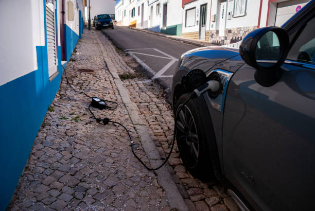 Electric car charging on the street. Cable from the house. stock photo