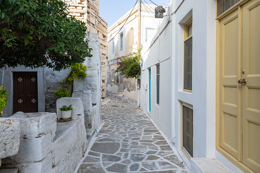Narrow street of the old town. Traditional, withe architecture and a stone path with white joints. Parikia, Paros Island, Greece.