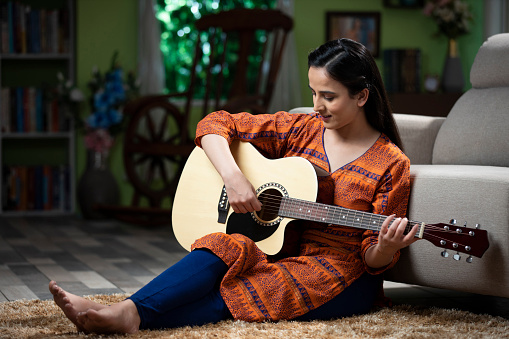 Sitting On Ground, using phone, Young Women, India, Indian ethnicity, music, guitar,
