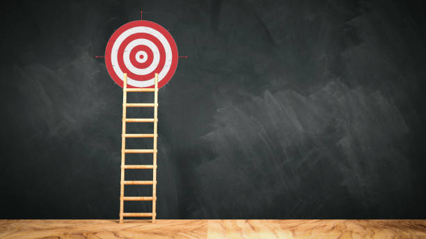 istock ladder leaning against a blackboard with a target symbol on it - 3d illustration 1306844191