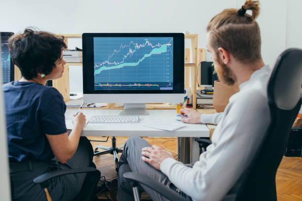 zwei kollegen analysieren ein finanzdiagramm auf einem computer - betrachtung grafiken stock-fotos und bilder