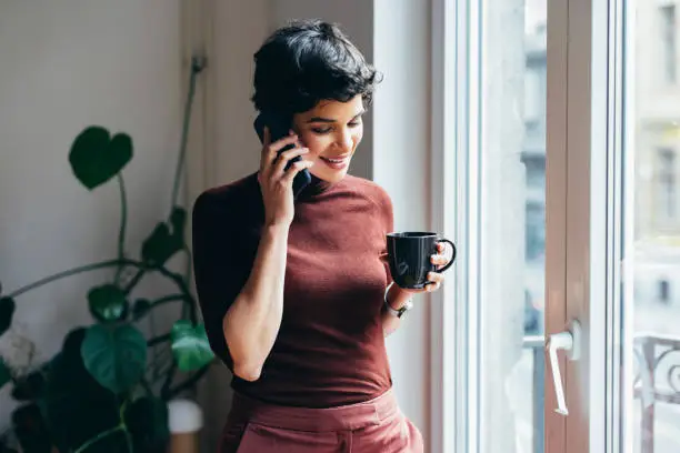 Photo of Beautiful Young Businesswoman Having a Conversation over the Phone while Holding a Cup of Coffee