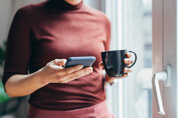 istock Anonymous Businesswoman Using her Smartphone and Drinking her Morning Coffee 1306844420