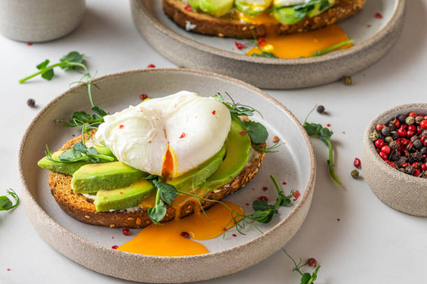 sandwichs à l’avocat, œuf poché, choux et fromage pour un petit déjeuner sain sur fond blanc. vue supérieure - pain tranché photos et images de collection