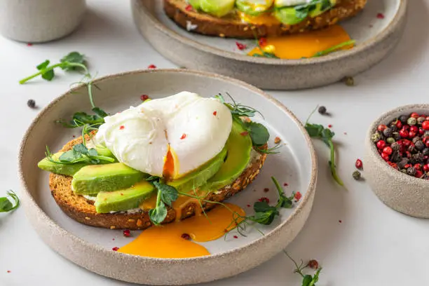 Sandwiches with avocado, poached egg, sprouts and cheese for healthy breakfast on white background. top view. Healthy diet food