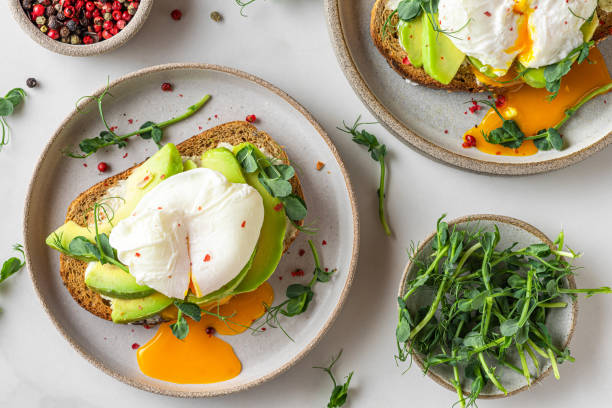 istock Sandwiches with avocado, poached egg, sprouts and cheese for healthy breakfast on white background. top view 1306846640