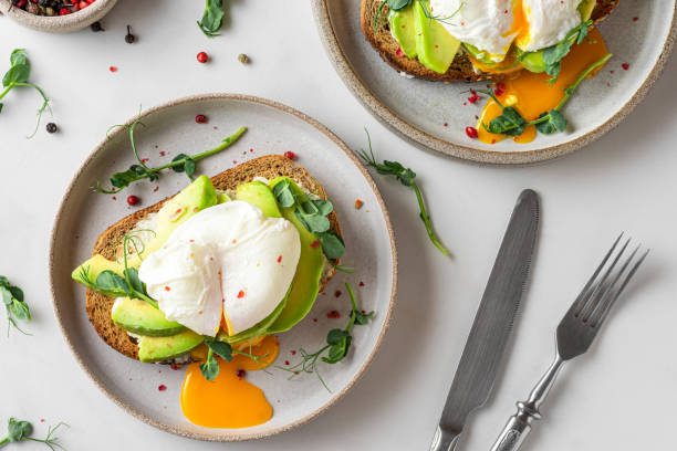 istock Healthy breakfast. Whole wheat toasted bread with avocado, poached egg, soft cheese and sprouts on white background 1306846655