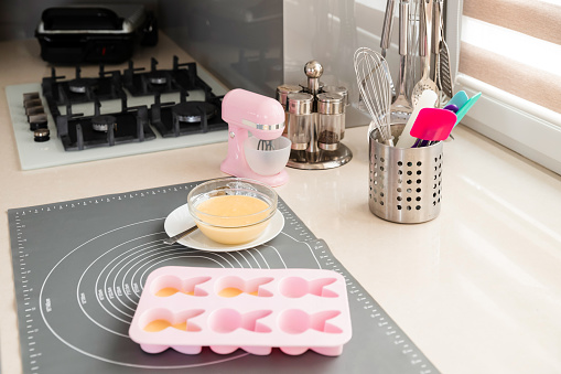 Baking utensils and ingredients. The process of unfolding raw dough into silicone cupcake molds for making homemade cakes.