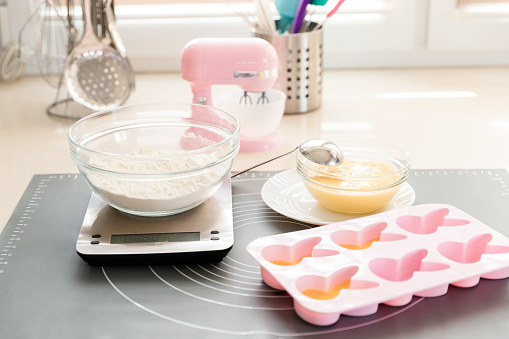 Baking utensils and ingredients. The process of unfolding raw dough into silicone cupcake molds for making homemade cakes.
