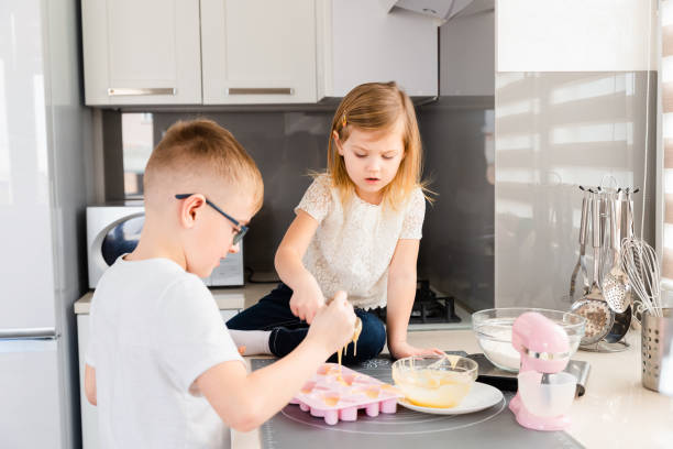 istock Little children cooking dough together in the kitchen 1306847109
