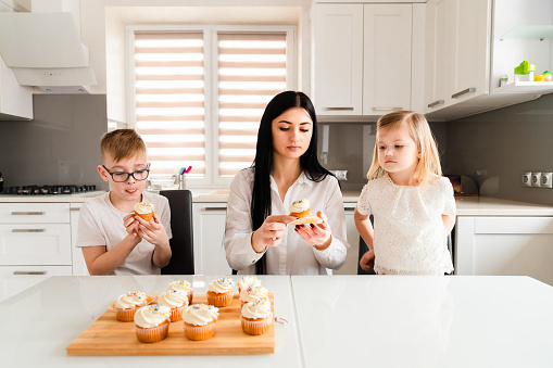 Mother with little children eat muffins