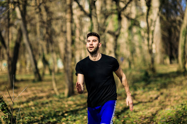 istock Running man in forest woods training and exercising for trail run marathon endurance race. Fitness healthy lifestyle concept with male athlete trail runner. 1306848082