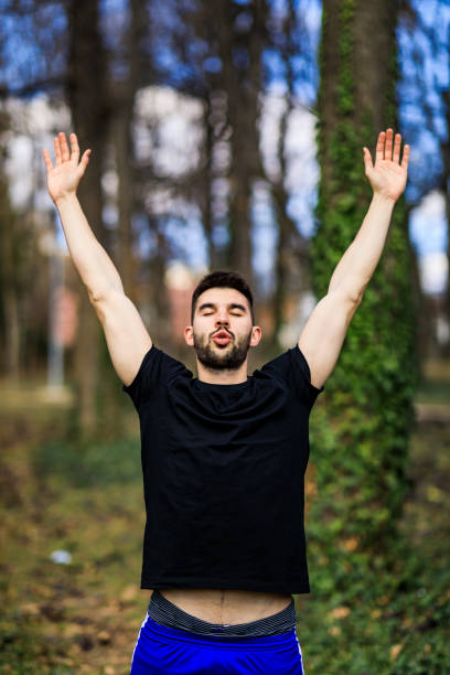 istock Young man breathing fresh air stretching arms in a park 1306848117