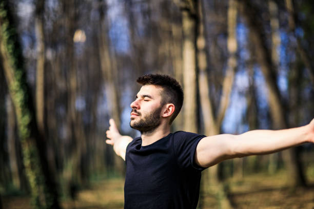 istock Young man breathing fresh air stretching arms in a park 1306848119
