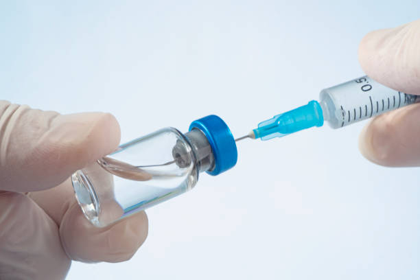 doctor draws medicine solution into syringe from vial on blue background. doctor hands and ampoule doctor hands and ampoule on on blue background. doctor draws medicine solution into syringe from vial on white background crista ampullaris photos stock pictures, royalty-free photos & images