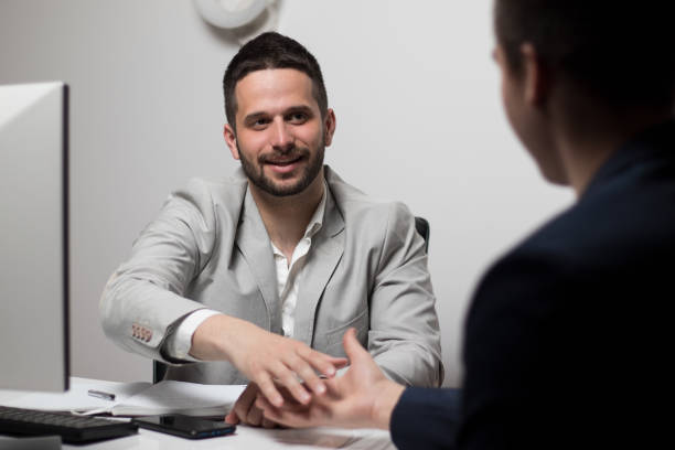 istock Happy young male colleagues shaking hands in office 1306850021